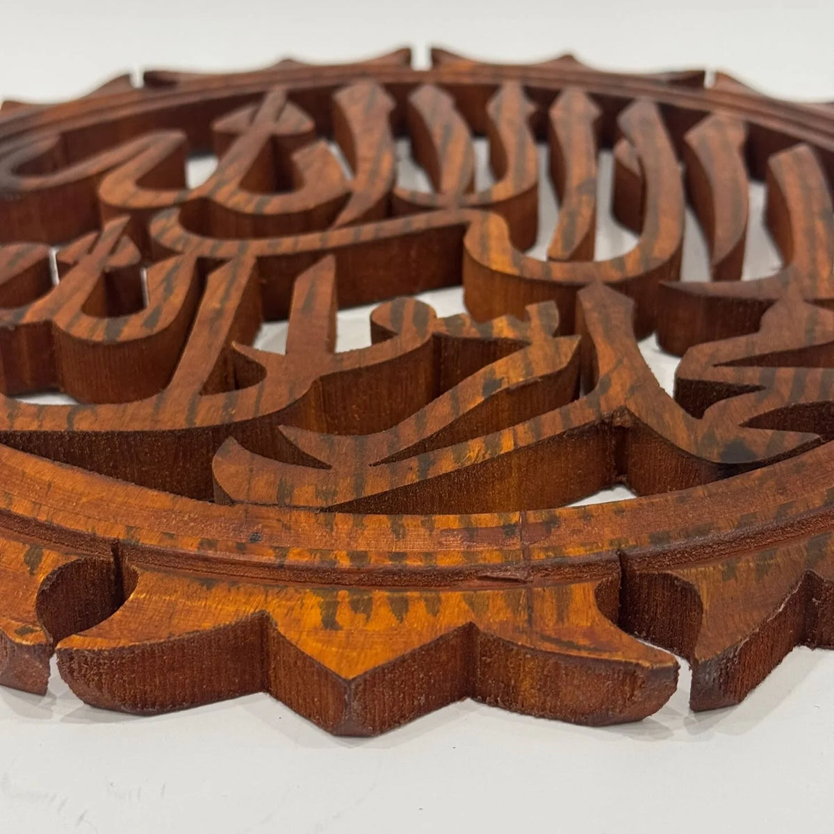 Close-up of the carved Allahu Akbar lettering and rounded wooden frame