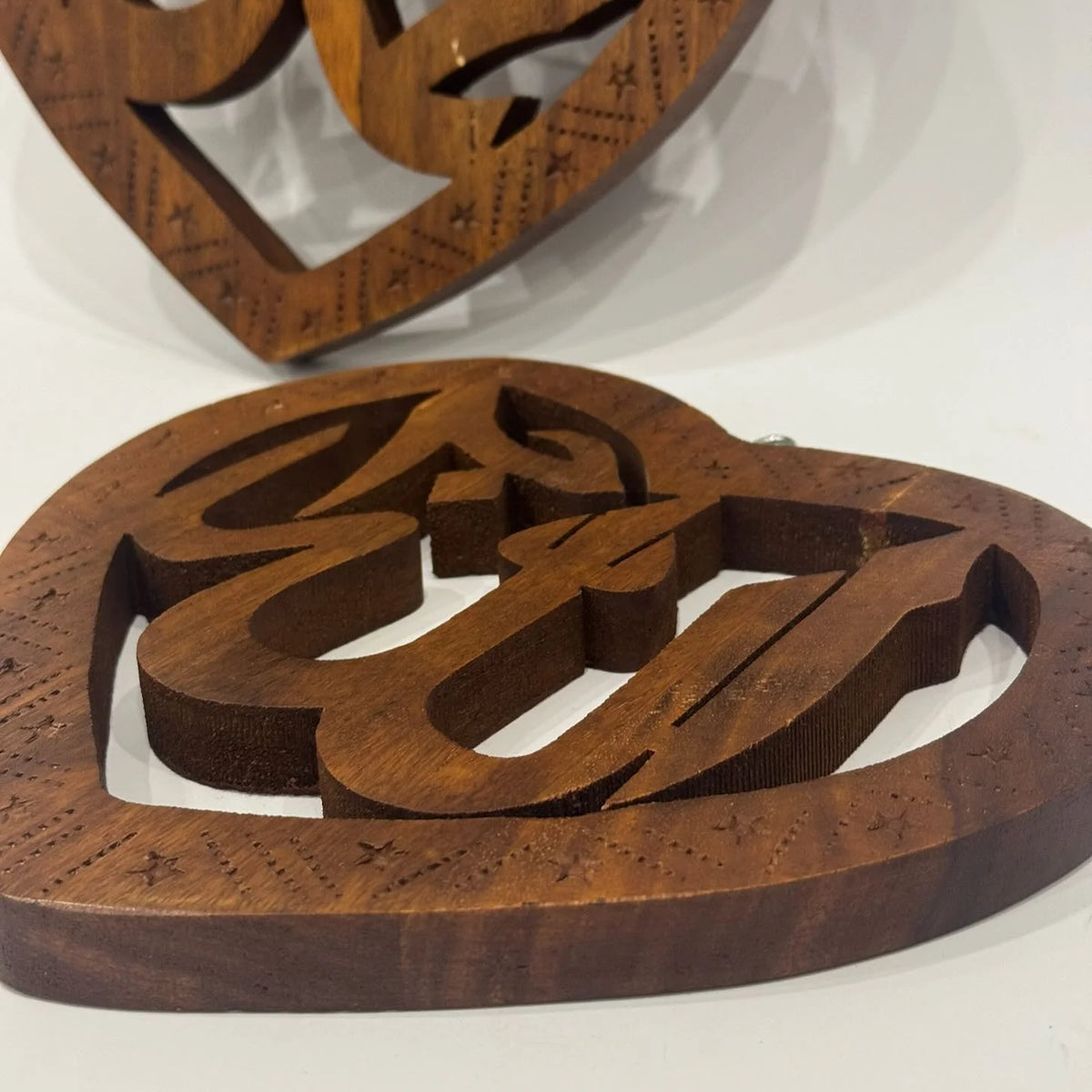 Close-up of the heart shaped Muhammad (SAW) wooden calligraphy plaque showing the carved lettering and star border