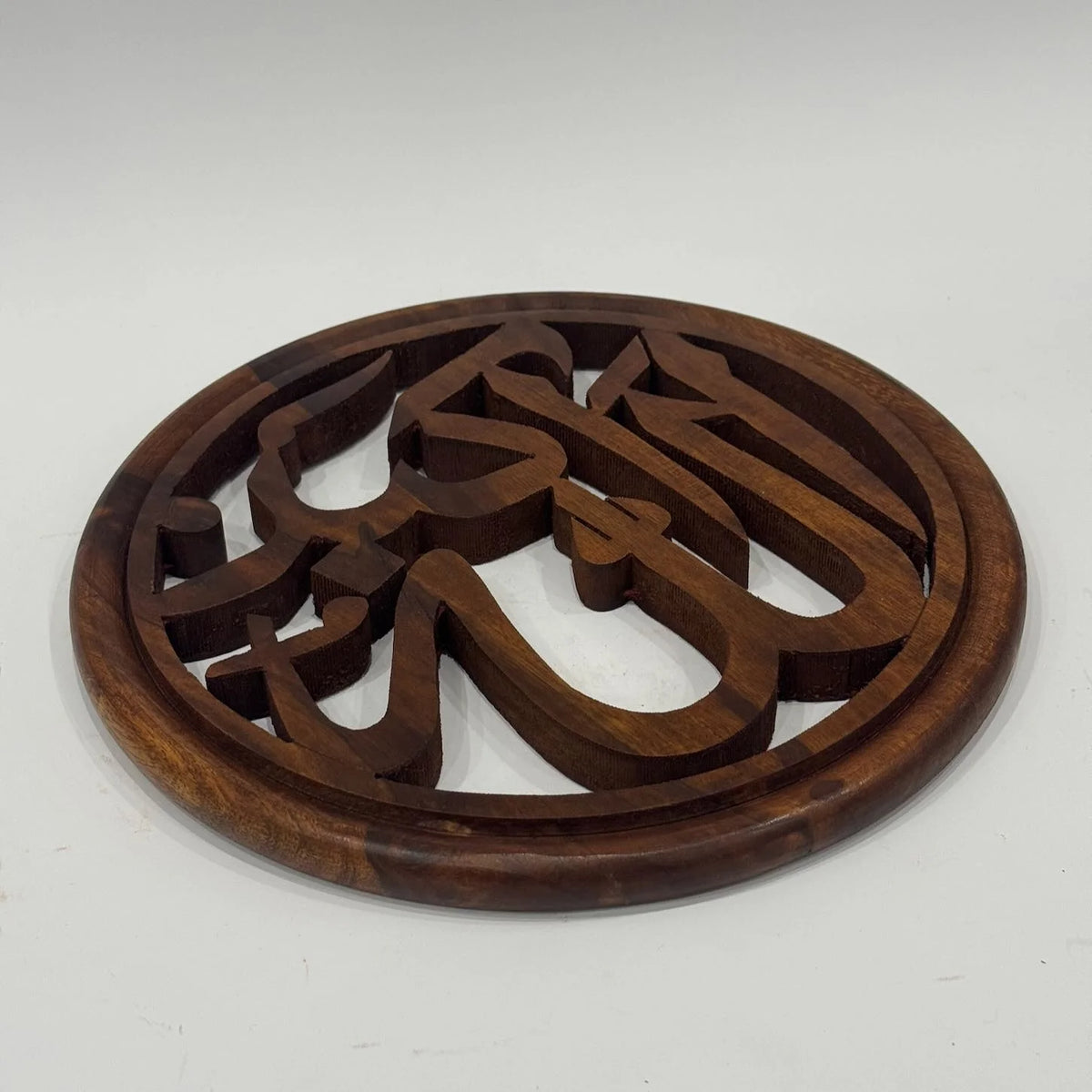 Round wooden Masha'Allah calligraphy wall hanging at an angle, showing the thickness of the carved letters