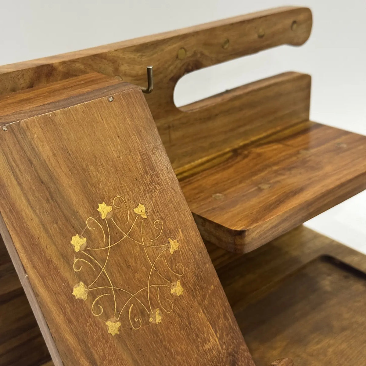 Close-up of brass inlay floral motif on the phone stand panel of a wooden desk organizer