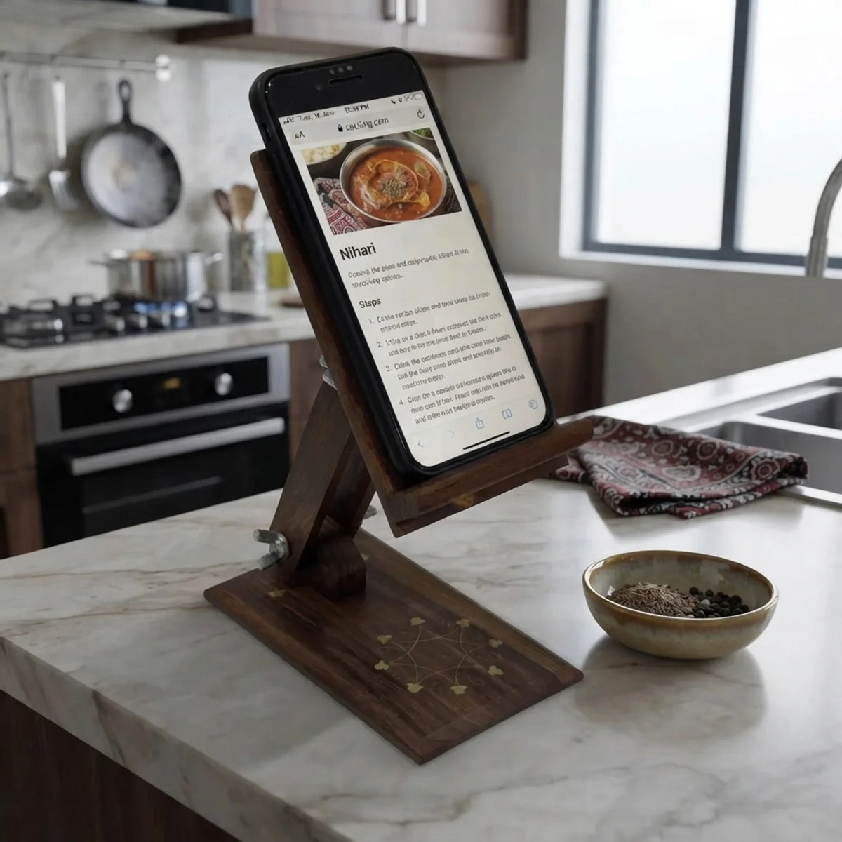 Brass inlay wooden mobile stand holding a phone with a recipe on a kitchen counter