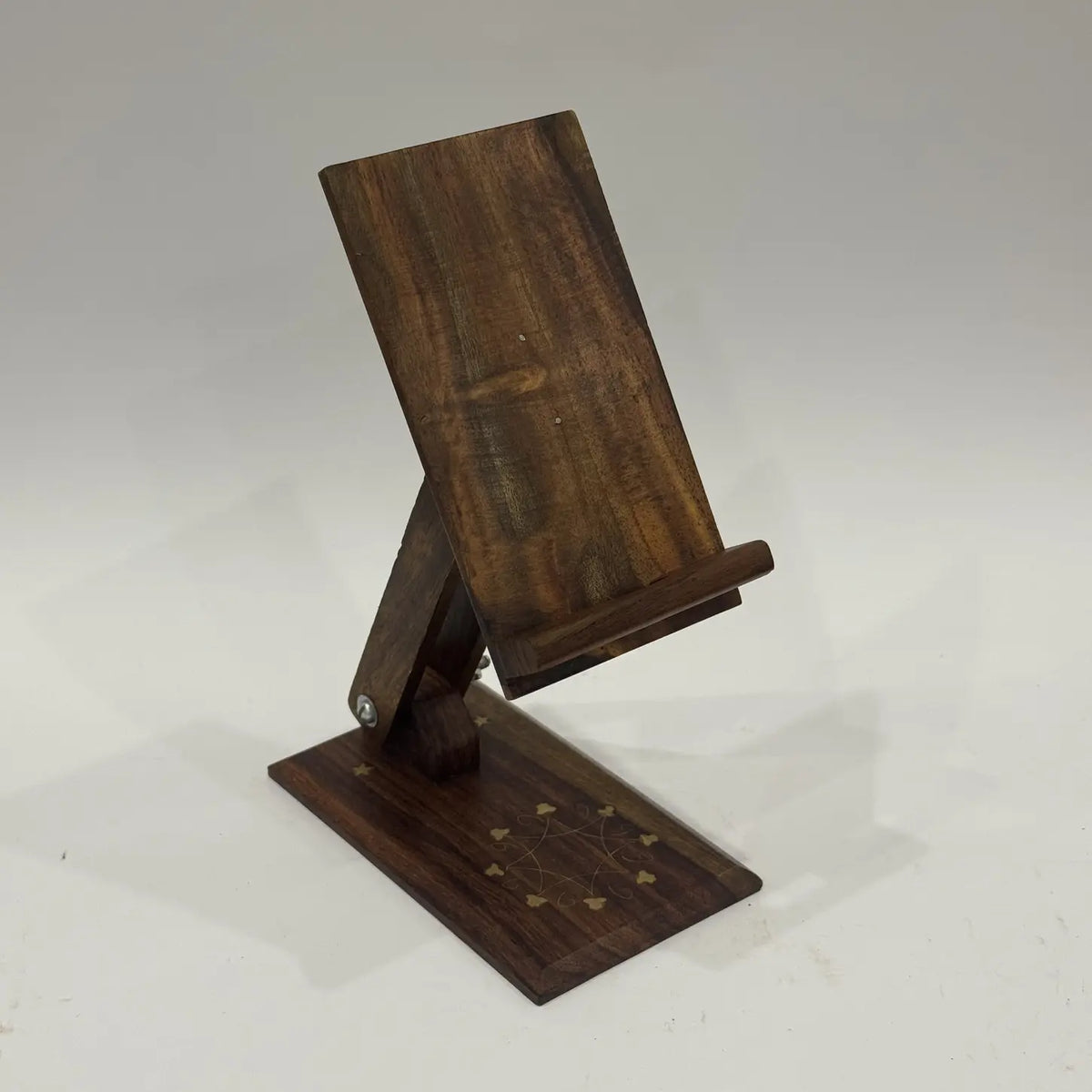 Wooden mobile holder stand with floral brass inlay on the base, front view