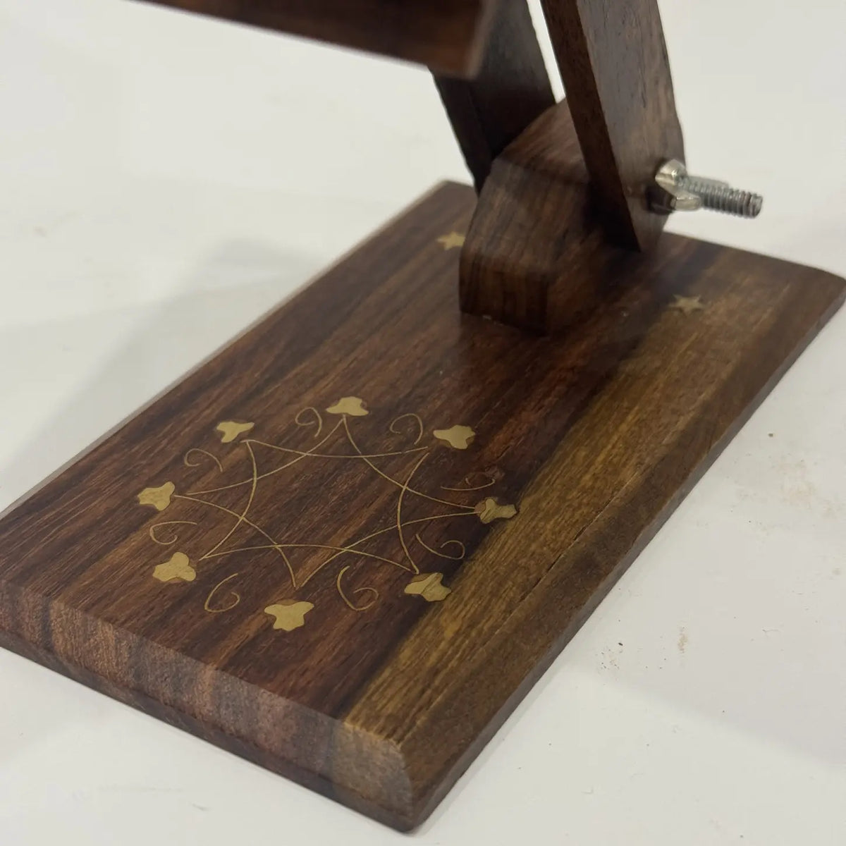 Close-up of floral brass inlay and brass star details on a wooden mobile stand base