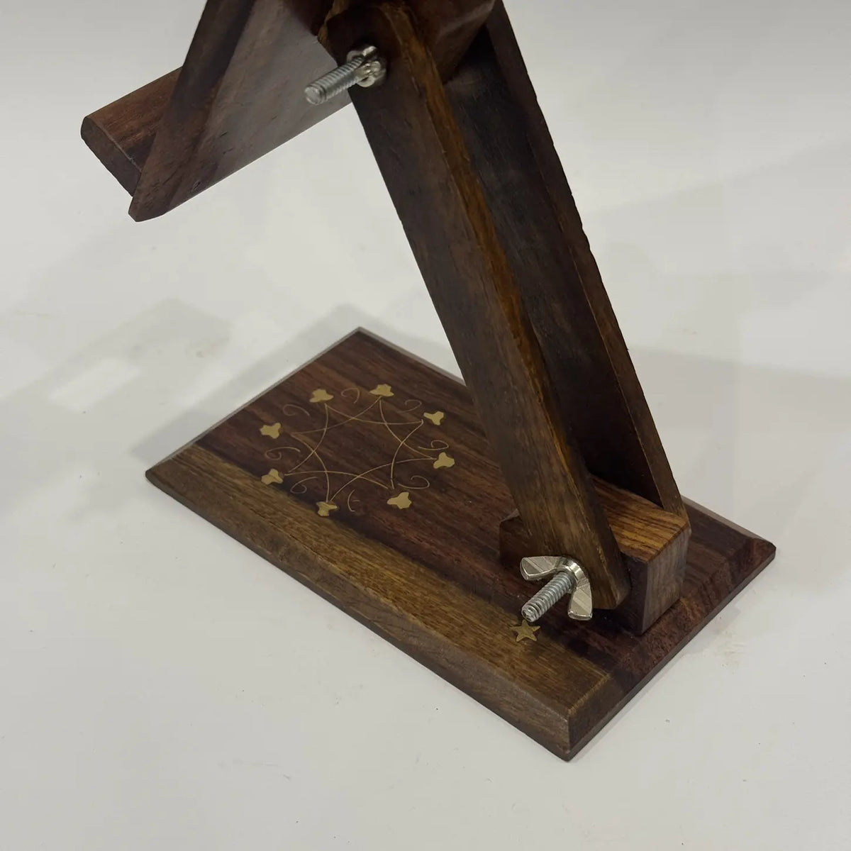 Adjustable arm and wing nuts on a brass inlay wooden phone stand, close-up