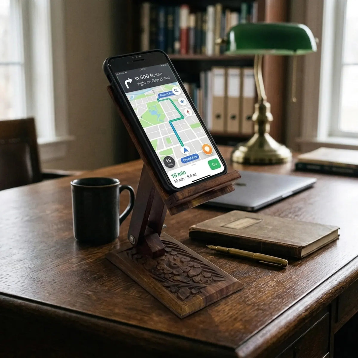 Hand carved wooden mobile stand holding a smartphone showing maps on a classic wooden desk