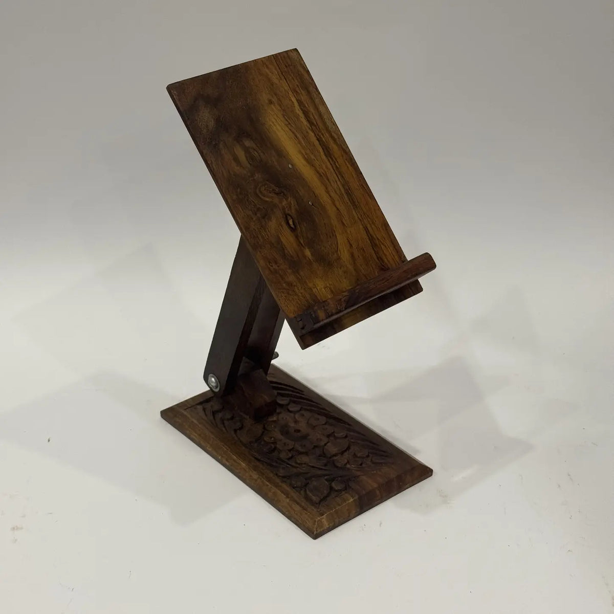 Hand carved sheesham wood mobile stand with floral carving on the base, front view
