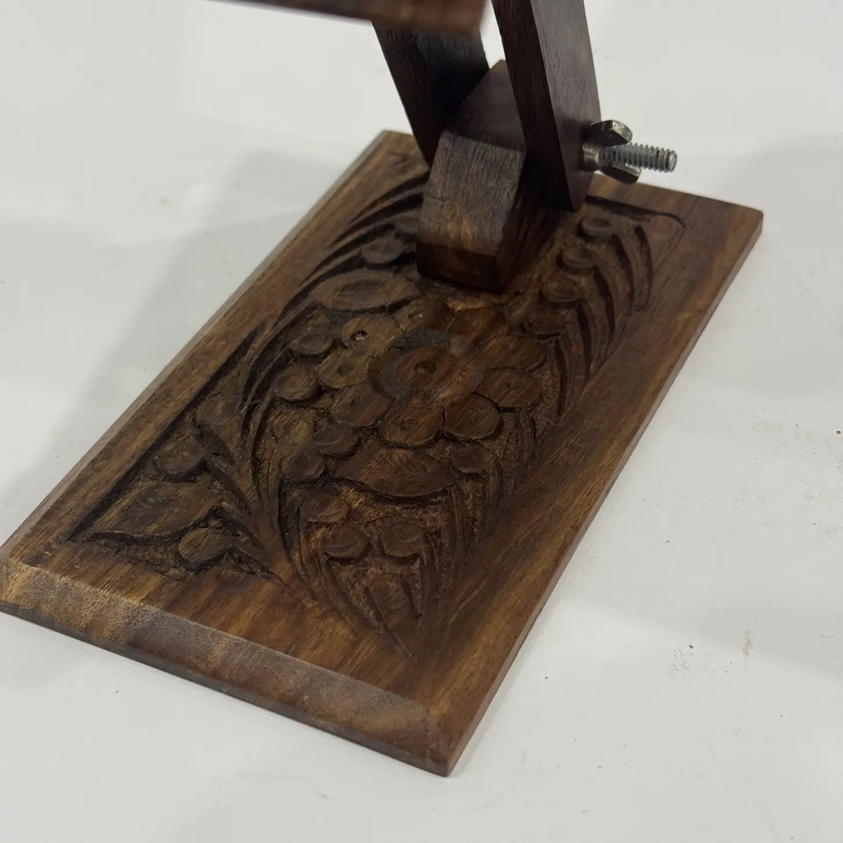 Close-up of hand carved floral pattern on a wooden mobile stand base