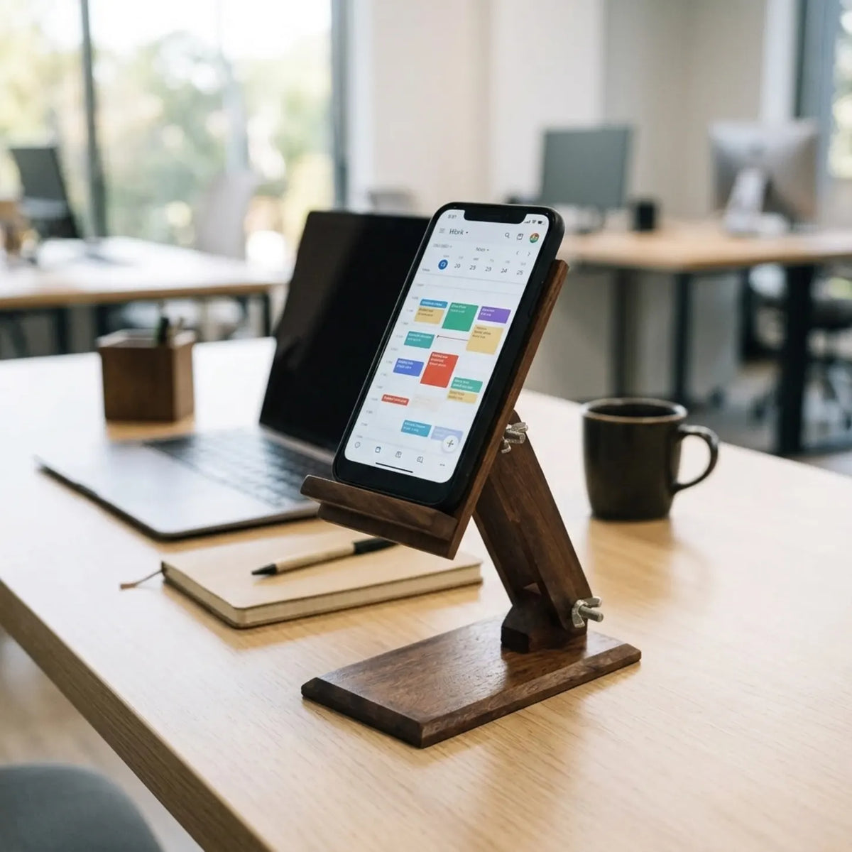 Plain sheesham wood adjustable mobile stand holding a smartphone on an office desk beside a laptop and coffee mug