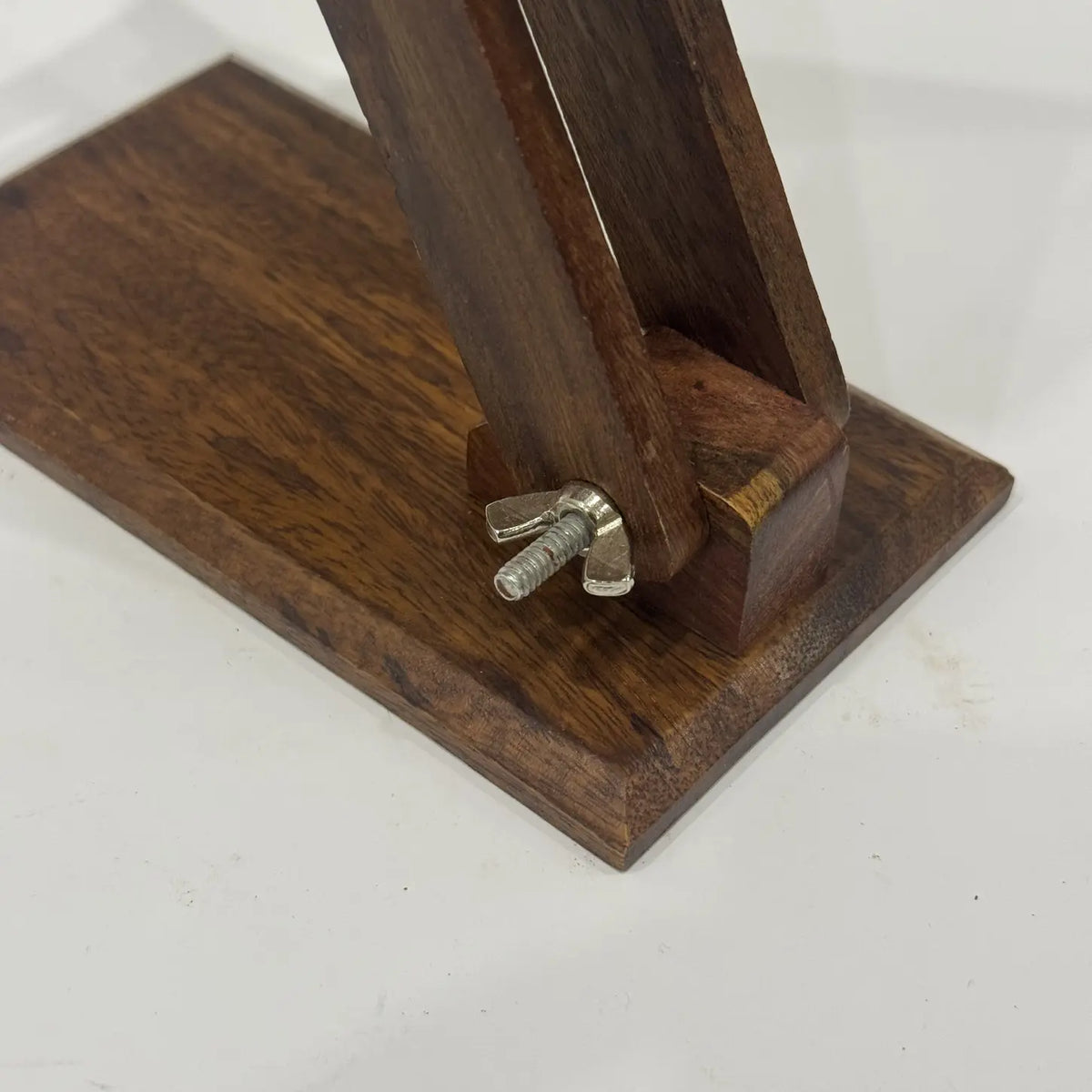 Close-up of plain wooden phone stand base with wing nut for adjusting the angle