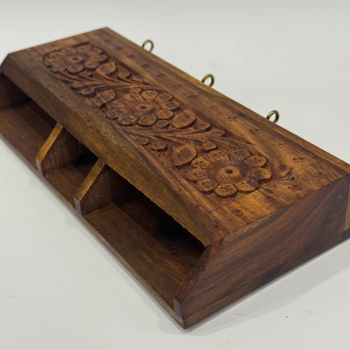 Top view of carved wooden wall organizer showing three compartments for phone, remote and small items
